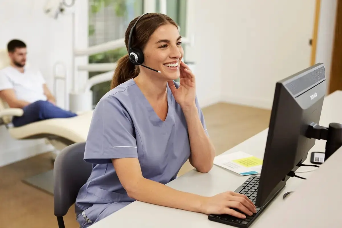 A dental clinic receptionist confirming an appointment on a headset